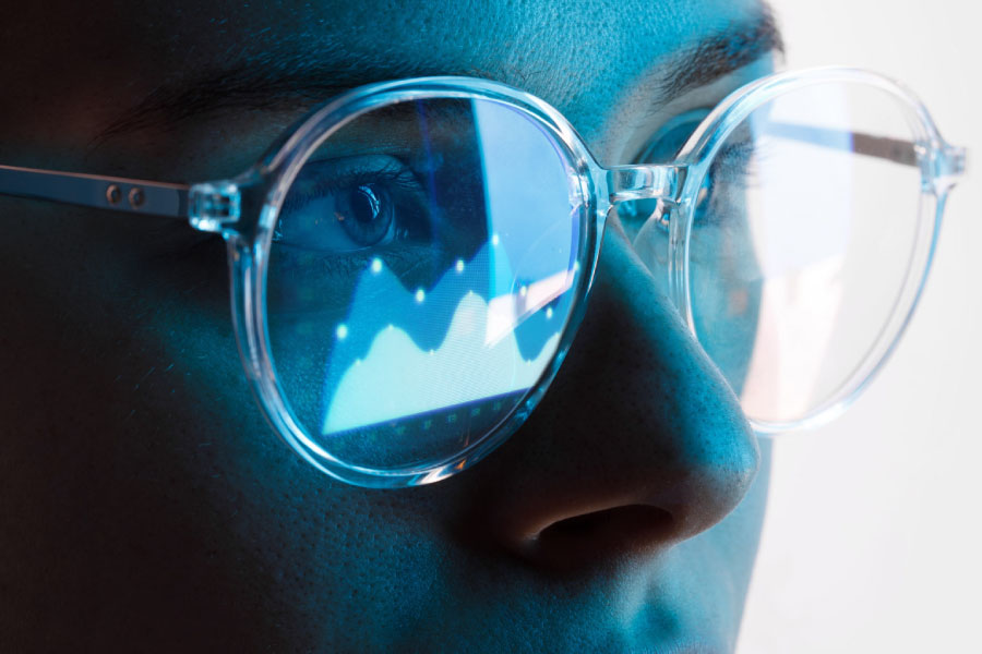 Person looking at a graph on the computer with glasses on. You can see the graph through the reflection of their glasses.